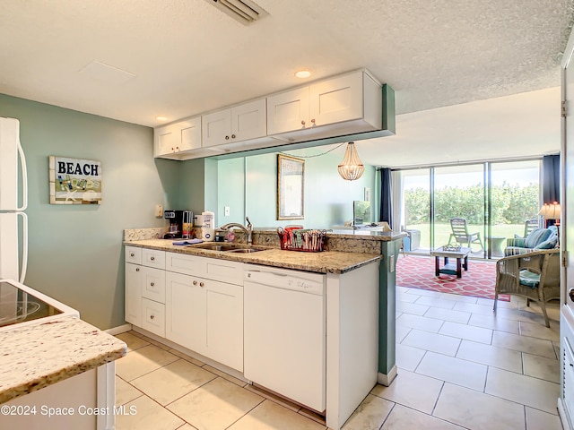 kitchen with white cabinetry, sink, light stone countertops, kitchen peninsula, and white appliances