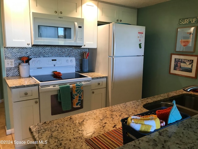 kitchen with light stone countertops, tasteful backsplash, white appliances, sink, and white cabinets