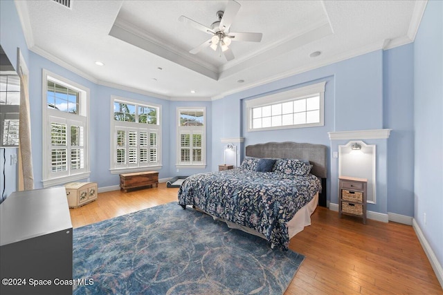 bedroom featuring a tray ceiling, crown molding, ceiling fan, and wood-type flooring