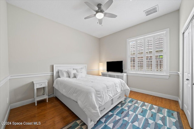 bedroom with dark hardwood / wood-style flooring, ceiling fan, a closet, and a textured ceiling