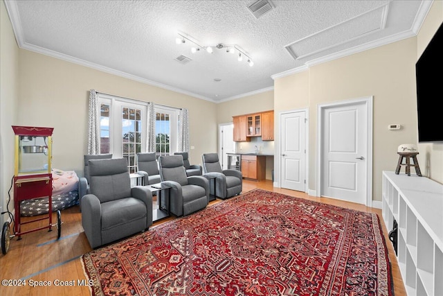 living room featuring crown molding, light hardwood / wood-style flooring, track lighting, and a textured ceiling