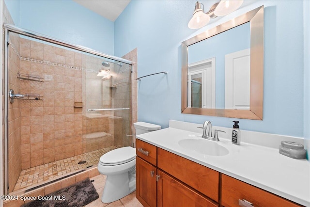 bathroom featuring tile patterned flooring, vanity, toilet, and a shower with shower door