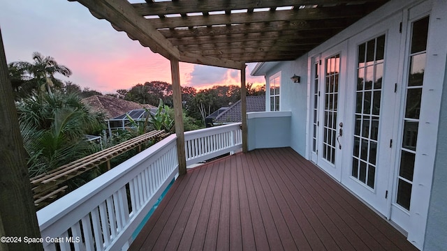 deck at dusk featuring french doors and a pergola