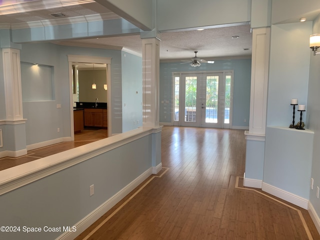 corridor featuring french doors, ornate columns, crown molding, sink, and wood-type flooring