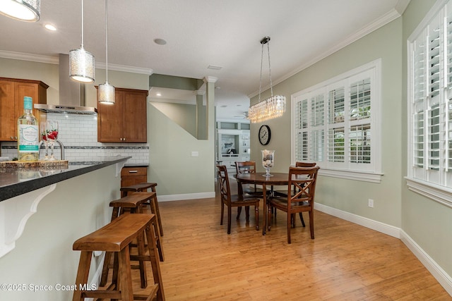 dining room with ornamental molding, light wood-type flooring, recessed lighting, and baseboards