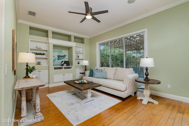 living area featuring visible vents, baseboards, a ceiling fan, light wood-style flooring, and ornamental molding