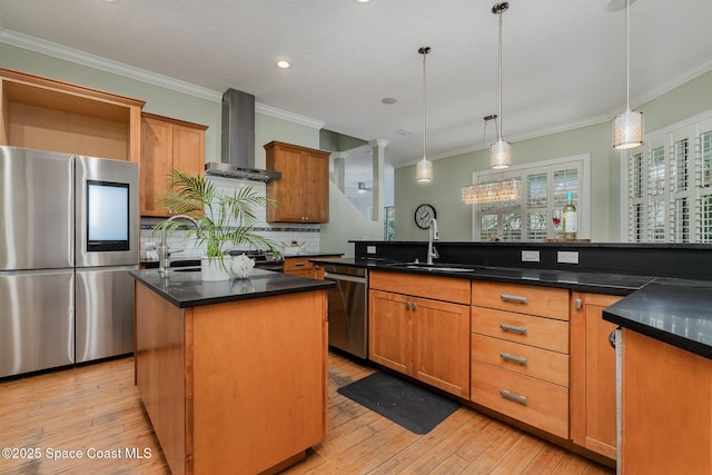 kitchen featuring an island with sink, dark countertops, appliances with stainless steel finishes, wall chimney range hood, and a sink