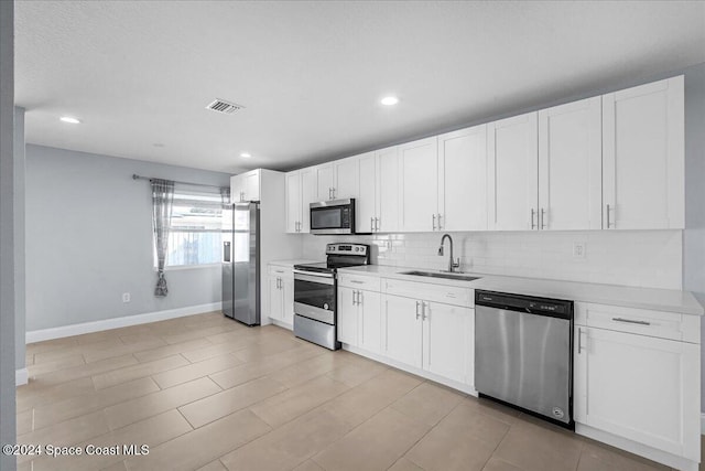 kitchen featuring white cabinetry, backsplash, appliances with stainless steel finishes, and sink