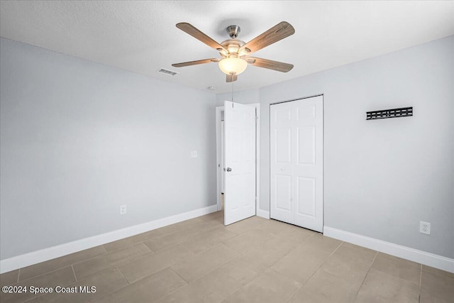 unfurnished bedroom featuring light tile patterned flooring, a closet, and ceiling fan