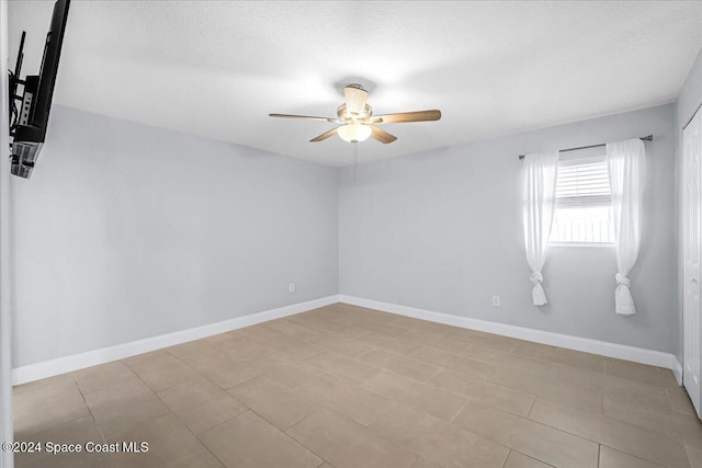 empty room with a textured ceiling, light tile patterned floors, and ceiling fan