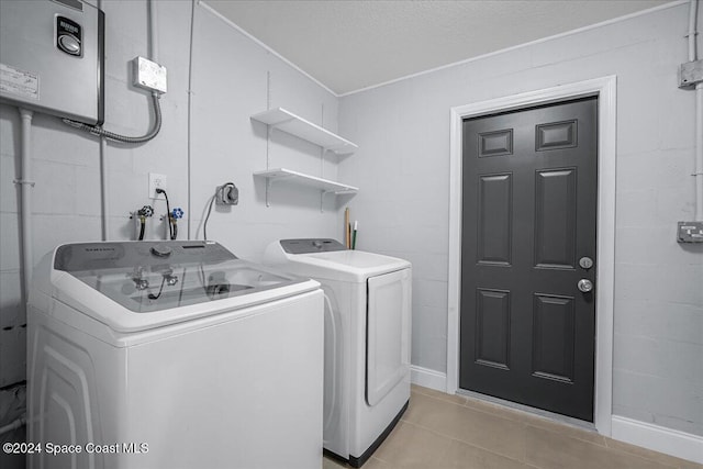 clothes washing area with a textured ceiling, washing machine and dryer, and light tile patterned floors