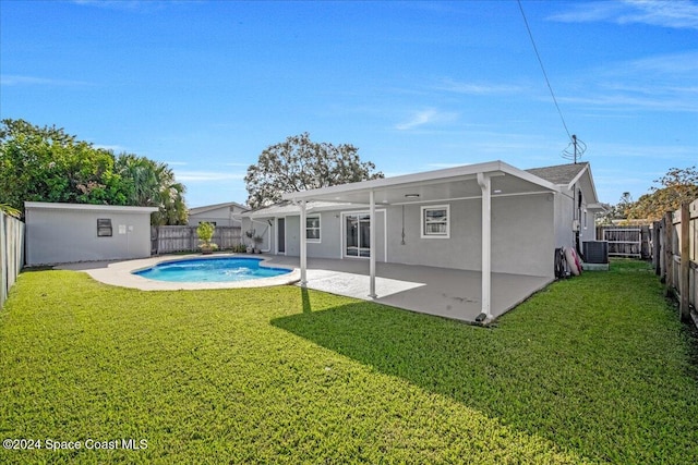 rear view of property with central air condition unit, a storage unit, a lawn, a patio, and a fenced in pool