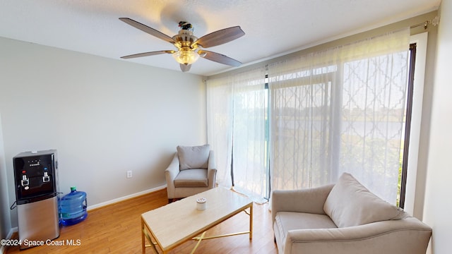 living area with ceiling fan, hardwood / wood-style flooring, and plenty of natural light