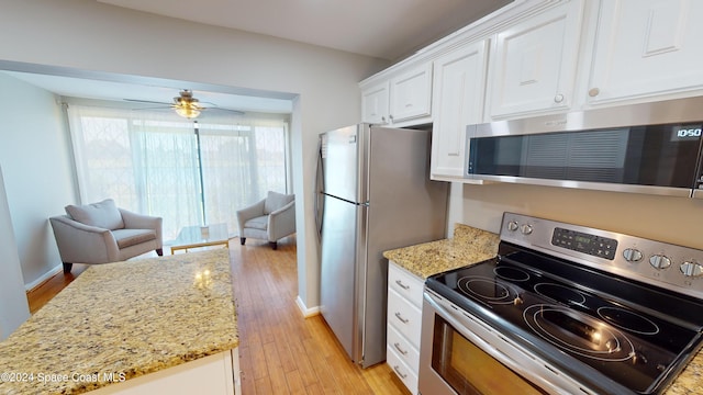 kitchen with stainless steel appliances, white cabinets, light stone counters, light hardwood / wood-style floors, and ceiling fan