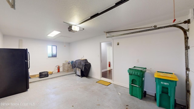 garage with a garage door opener and black refrigerator