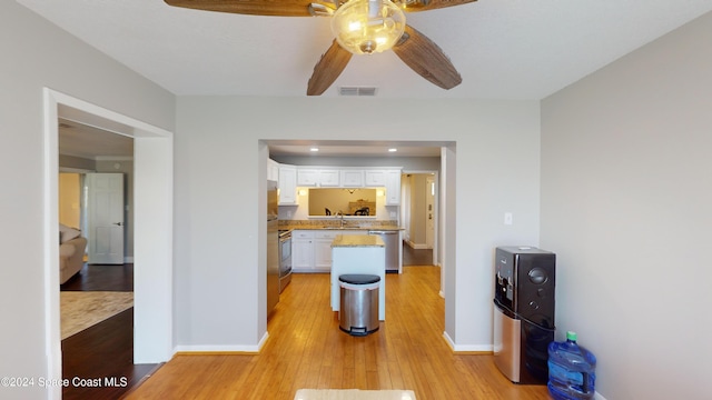 kitchen featuring ceiling fan, appliances with stainless steel finishes, white cabinetry, light hardwood / wood-style flooring, and sink