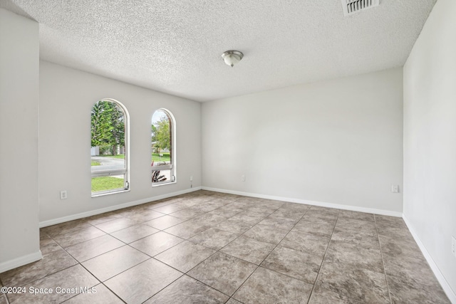 unfurnished room with a textured ceiling and light tile patterned flooring