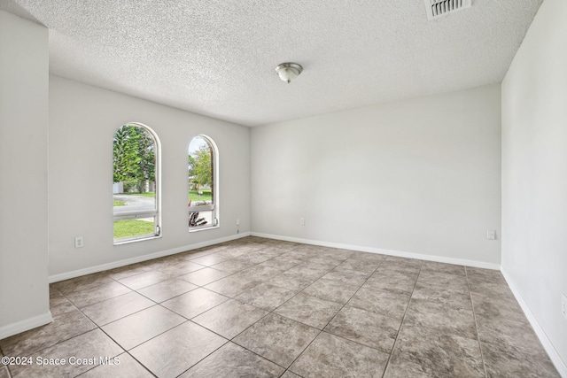 unfurnished room featuring a textured ceiling and tile patterned flooring