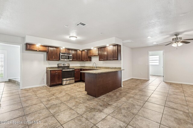 kitchen with stainless steel appliances, a sink, light tile patterned flooring, baseboards, and a textured ceiling
