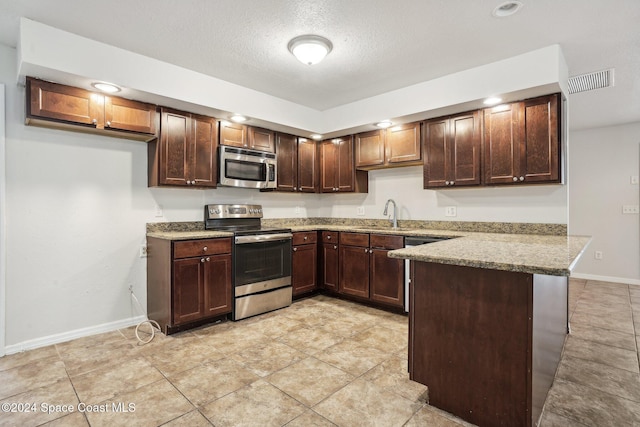 kitchen with stainless steel appliances, a peninsula, baseboards, light stone countertops, and a sink