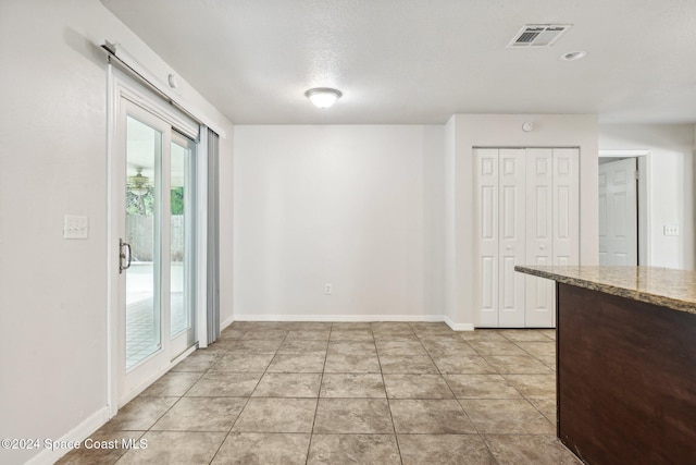 unfurnished dining area with a textured ceiling and light tile patterned flooring