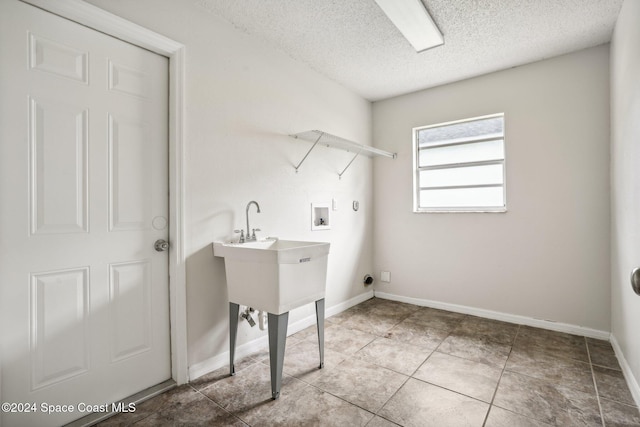 laundry room with hookup for a washing machine, a textured ceiling, hookup for a gas dryer, and light tile patterned flooring