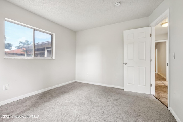 unfurnished room with carpet flooring and a textured ceiling