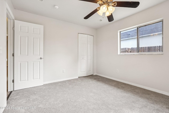 unfurnished bedroom with carpet floors, a closet, baseboards, and a ceiling fan