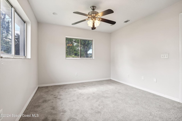 carpeted spare room featuring a ceiling fan and baseboards