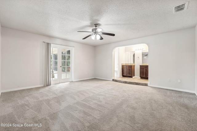 spare room with french doors, a textured ceiling, light colored carpet, and ceiling fan