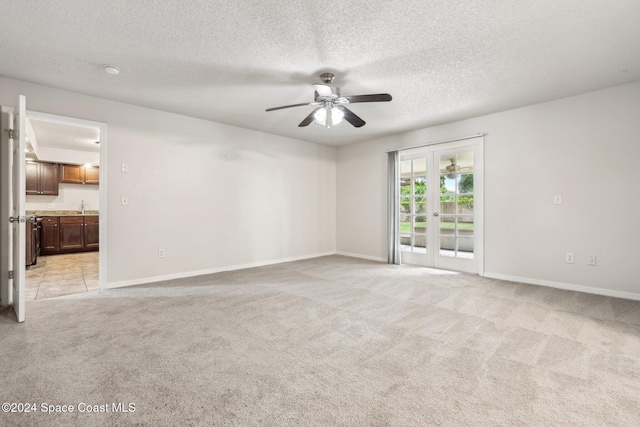 spare room with a ceiling fan, light carpet, baseboards, a sink, and a textured ceiling