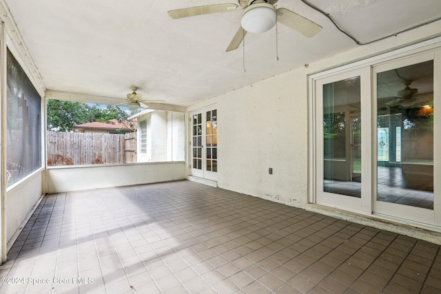unfurnished sunroom featuring a ceiling fan and plenty of natural light
