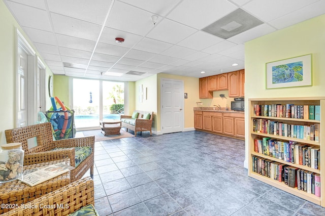 living area with a paneled ceiling and sink