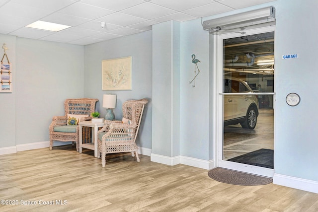 sitting room with a paneled ceiling and light wood-type flooring