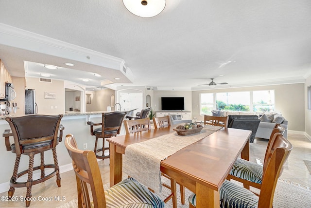 tiled dining room featuring ceiling fan, crown molding, and a textured ceiling