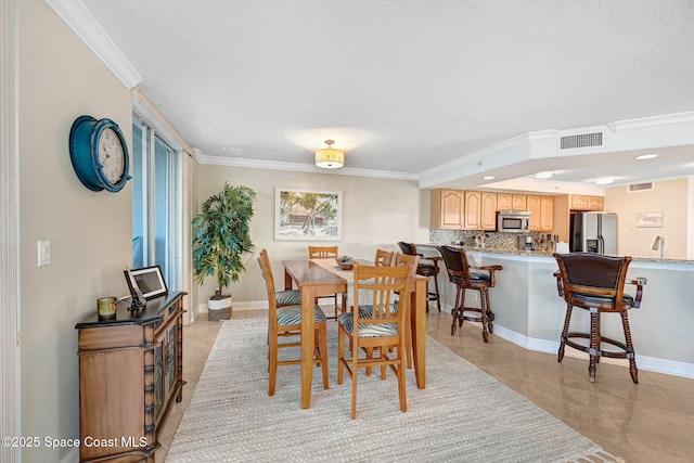 dining area featuring sink, light tile patterned floors, and crown molding