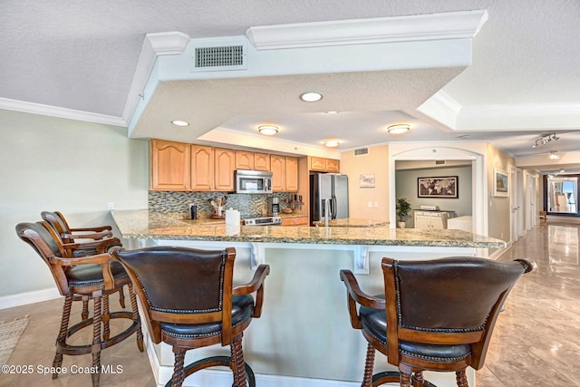 kitchen featuring kitchen peninsula, backsplash, a textured ceiling, stainless steel appliances, and a tray ceiling