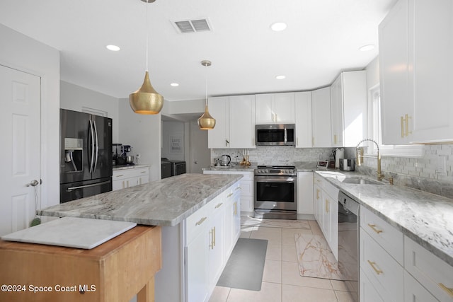 kitchen featuring light stone countertops, a center island, pendant lighting, white cabinets, and appliances with stainless steel finishes