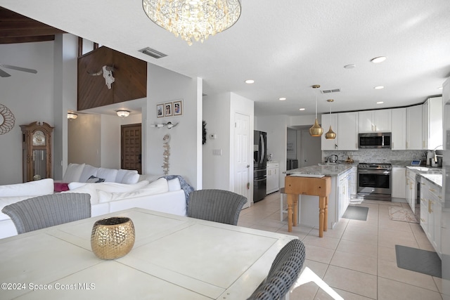 tiled dining space with ceiling fan with notable chandelier