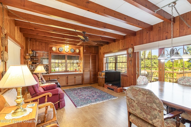 living room with beam ceiling, hardwood / wood-style floors, ceiling fan, and wood walls