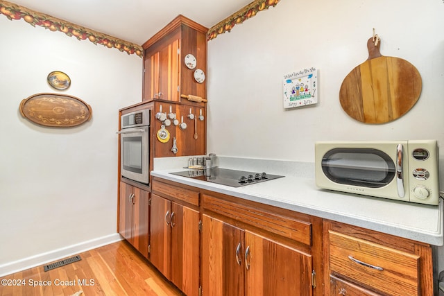 kitchen with oven, black electric cooktop, and light wood-type flooring