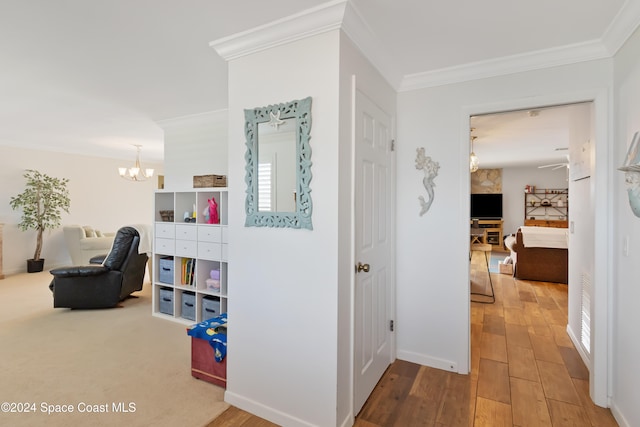 corridor featuring crown molding, hardwood / wood-style flooring, and a chandelier