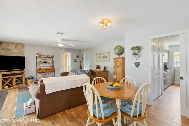 dining area with light hardwood / wood-style flooring, a textured ceiling, and ceiling fan