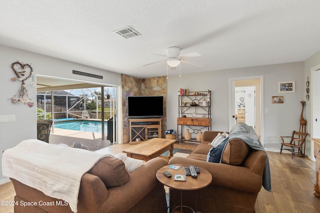 living room with hardwood / wood-style floors, a textured ceiling, and ceiling fan