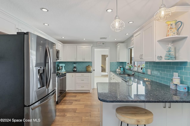 kitchen with appliances with stainless steel finishes, sink, light hardwood / wood-style floors, pendant lighting, and white cabinets