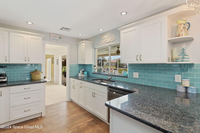 kitchen featuring backsplash, white cabinetry, light wood-type flooring, dark stone counters, and sink