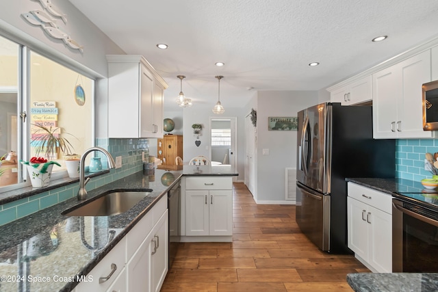 kitchen with decorative backsplash, sink, pendant lighting, white cabinetry, and light hardwood / wood-style floors