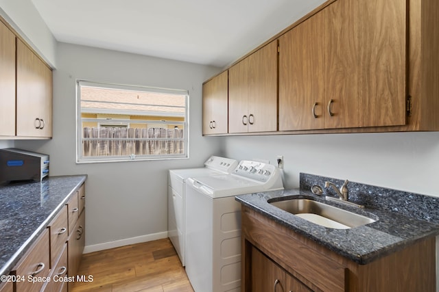 laundry area featuring sink, independent washer and dryer, cabinets, and light hardwood / wood-style flooring