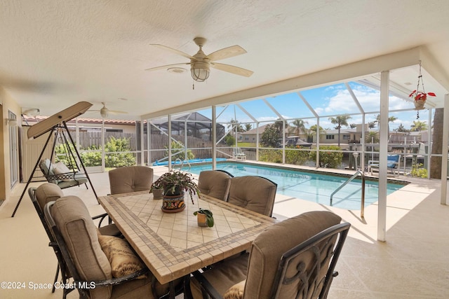 view of swimming pool with ceiling fan, a patio area, and a lanai