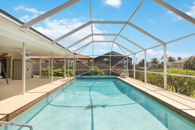 view of pool with a patio area, ceiling fan, and glass enclosure